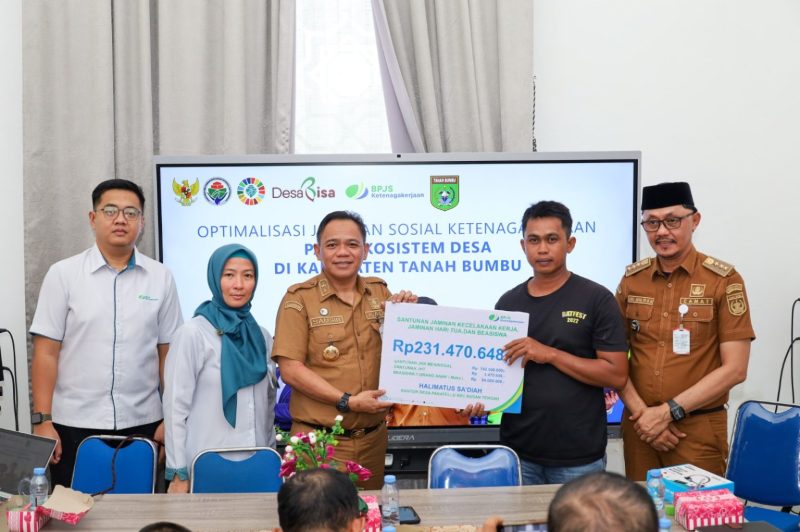 Kepala Dinas PMD Tanah Bumbu, Syamsir, menyerahkan santunan BPJS Ketenagakerjaan sebesar Rp231 juta kepada ahli waris almarhumah Halimatus Sa’diah dalam kegiatan sosialisasi program jaminan sosial ketenagakerjaan di Kecamatan Kusan Tengah, Senin (14/7/2024). Turut hadir Kepala BPJS Ketenagakerjaan Batulicin, Vina Dwina Yuskin, dan camat setempat.