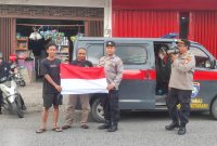 Personel Satbinmas Polres Kotabaru membagikan bendera Merah Putih kepada warga sambil menyampaikan imbauan pengibaran bendera menjelang HUT ke-80 RI, Kamis (31/7/2025). (Foto: Humas Polres Kotabaru)
