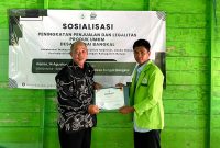 Ketua Kelompok KKN Desa Sungai Bangkal, Ikhsan Abdullah (kanan), menyerahkan sertifikat kepada Kepala Bidang Usaha Mikro DKUMPP Kabupaten Banjar, Rudy Mulyadi, usai sosialisasi peningkatan penjualan dan legalitas produk UMKM di Desa Sungai Bangkal, Kamis (14/8/2025).