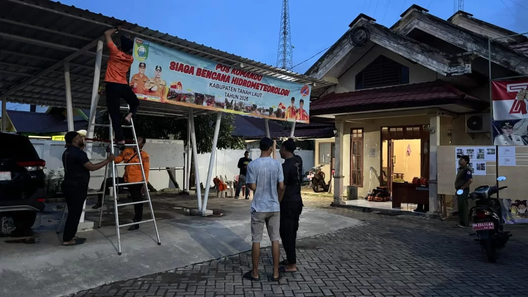 Petugas BPBD bersama relawan memasang spanduk Pos Komando Siaga Bencana Hidrometeorologi Kabupaten Tanah Laut Tahun 2026 di salah satu titik kesiapsiagaan, Sabtu (3/1/2026).