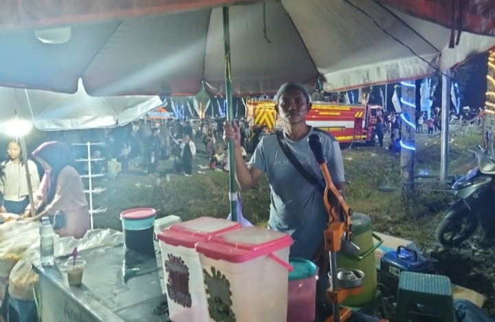 Suparman, pedagang es jus dan es kelapa muda, melayani pembeli di Aksi Inovasi Tanbu 2026 di Simpang Empat, Sabtu (04/04/2026) malam.