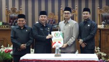 Pimpinan DPRD Tanah Bumbu bersama perwakilan pemerintah daerah menunjukkan dokumen persetujuan saat rapat paripurna pengambilan keputusan pencabutan Perda Nomor 6 Tahun 2020 tentang perubahan status Kelurahan Batulicin, Rabu (06/05/2026).