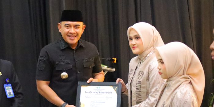 Bupati Tanah Laut H. Rahmat Trianto menyerahkan penghargaan kepada salah satu siswi berprestasi dalam prosesi pengukuhan dan pelepasan siswa kelas XII MAN Insan Cendekia Tanah Laut tahun ajaran 2025/2026