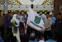 Sekda Tanah Bumbu Yulian Herawati secara simbolis menyerahkan bendera daerah saat pelepasan 239 Jamaah Calon Haji kloter 13 dan 18 asal Kabupaten Tanah Bumbu di Masjid Agung Nurussalam, Batulicin, Kamis (07/05/2026).