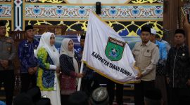 Sekda Tanah Bumbu Yulian Herawati secara simbolis menyerahkan bendera daerah saat pelepasan 239 Jamaah Calon Haji kloter 13 dan 18 asal Kabupaten Tanah Bumbu di Masjid Agung Nurussalam, Batulicin, Kamis (07/05/2026).