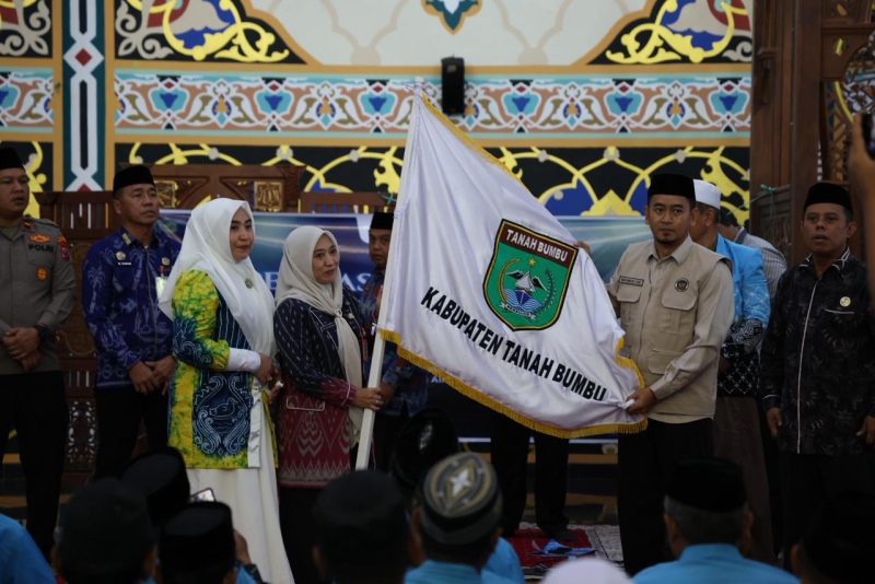 Sekda Tanah Bumbu Yulian Herawati secara simbolis menyerahkan bendera daerah saat pelepasan 239 Jamaah Calon Haji kloter 13 dan 18 asal Kabupaten Tanah Bumbu di Masjid Agung Nurussalam, Batulicin, Kamis (07/05/2026).