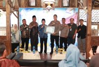 Asisten Perekonomian dan Pembangunan Setda Tanah Bumbu, Eryanto Rais, menyerahkan Sertifikat Penghargaan kepada Kapolres Tanah Bumbu sebagai bentuk apresiasi Pemerintah Kabupaten Tanah Bumbu atas inovasi pelayanan publik Kopi Manis (Kantor Polisi Keliling Humanis), usai pembukaan Pelatihan Bahasa Mandarin Tahun 2026, Jumat (12/6/2026).
