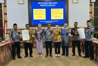 Jajaran KemenPPPA, Pemkab Tanah Laut, camat, dan kepala desa menunjukkan dokumen komitmen pelaksanaan Ruang Bersama Indonesia (RBI) di Aula Bapperida Kabupaten Tanah Laut, Kamis (18/06/2026).