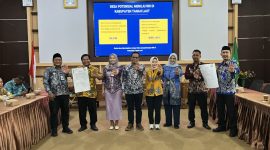 Jajaran KemenPPPA, Pemkab Tanah Laut, camat, dan kepala desa menunjukkan dokumen komitmen pelaksanaan Ruang Bersama Indonesia (RBI) di Aula Bapperida Kabupaten Tanah Laut, Kamis (18/06/2026).