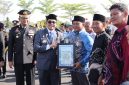 Bupati Tanah Bumbu Andi Rudi Latif menyerahkan piagam penghargaan kepada relawan kemanusiaan pada Apel Gabungan Peringatan Hari Bhayangkara ke-80 di halaman Mapolres Tanah Bumbu, Simpang Empat, Rabu (01/07/2026).