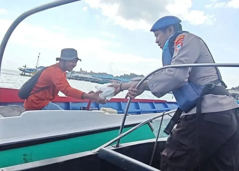 Personel Sat Polairud Polres Kotabaru menyerahkan paket makanan kepada seorang nelayan di perairan Selat Laut dalam kegiatan Jumat Berkah sebagai bentuk kepedulian kepada masyarakat pesisir, Jumat (31/07/2026).