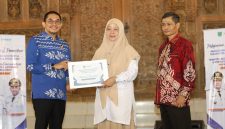 Bupati Tanah Bumbu menyerahkan santunan kepada perwakilan mahasiswa ULM dalam acara penarikan peserta KKN Tematik Lingkungan Hidup ULM Tahun 2026 di Tanah Bumbu.
