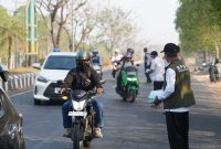 Petugas BPBD dan Dinas Kesehatan Tanah Bumbu membagikan masker gratis kepada masyarakat dan pengguna jalan sebagai langkah antisipasi dampak kabut asap karhutla.