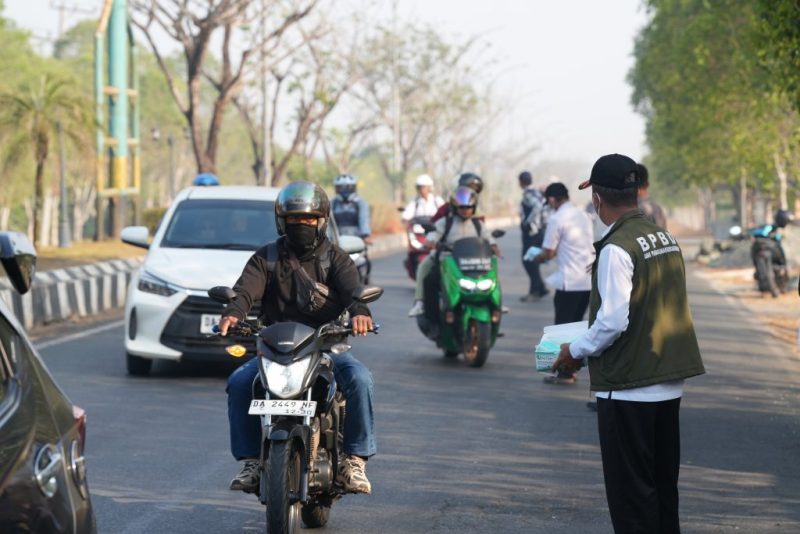 Petugas BPBD dan Dinas Kesehatan Tanah Bumbu membagikan masker gratis kepada masyarakat dan pengguna jalan sebagai langkah antisipasi dampak kabut asap karhutla.